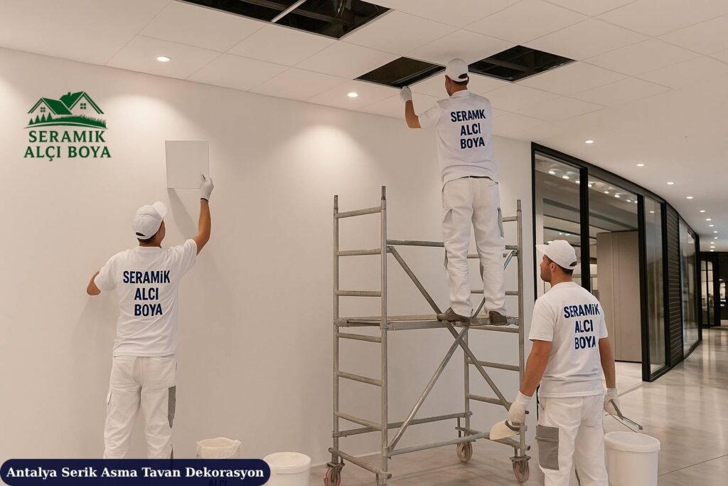 Antalya Serik Asma Tavan Dekorasyon 2025 3 Antalya Serik Asma Tavan Dekorasyon Serik’te alışveriş merkezi içindeki iş yerinde iki usta, Seramik Alçı Boya iş kıyafetleriyle modern asma tavan montajı yapıyor.