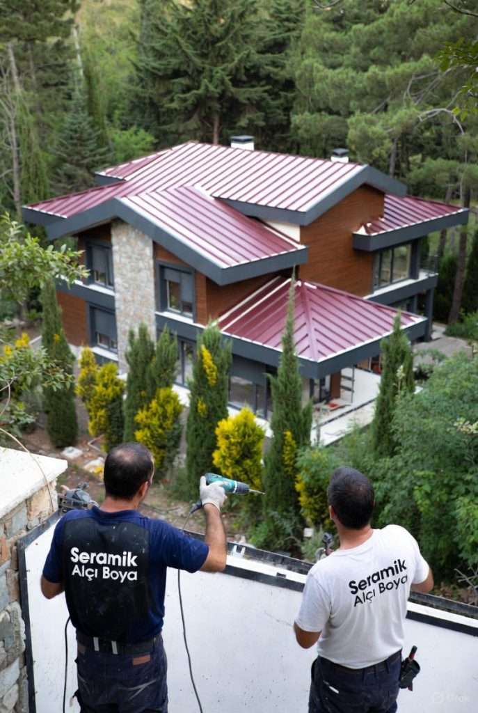 Antalya Belek Çatı Onarım ve Tadilat 2025, Belek’te modern mimarili 3 katlı villanın çatısına bordo renk 8 metrelik sandviç paneller profesyonel ekip tarafından monte ediliyor.